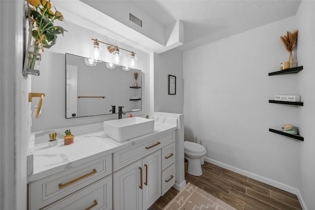 bathroom with wood-type flooring, vanity, a textured ceiling, and toilet