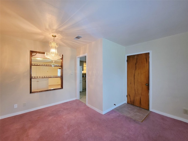 carpeted spare room with a notable chandelier