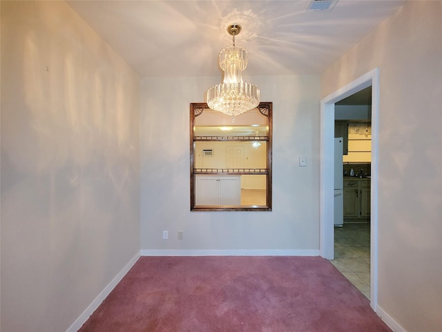 spare room with carpet and an inviting chandelier