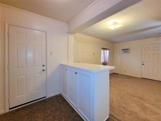 interior space with dark colored carpet, a textured ceiling, a wall mounted air conditioner, and crown molding