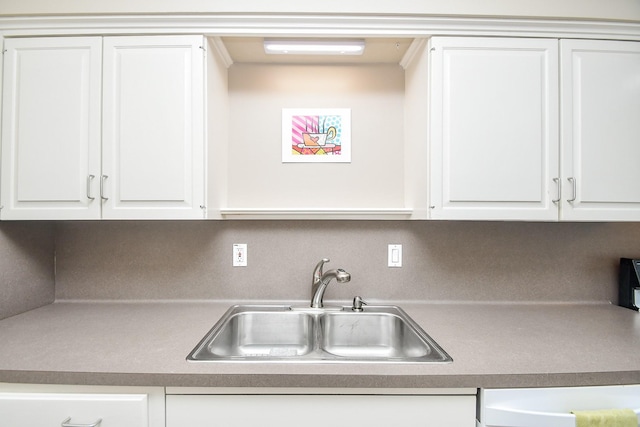 kitchen with tasteful backsplash, white cabinetry, and sink