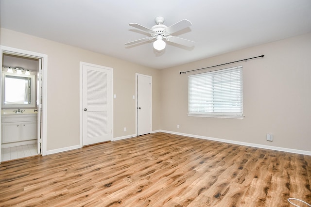 unfurnished bedroom featuring ensuite bathroom, ceiling fan, light wood-type flooring, and sink