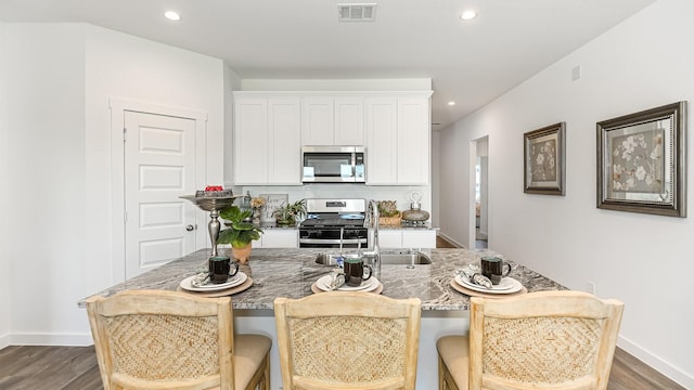 kitchen featuring sink, dark wood-type flooring, a breakfast bar area, white cabinets, and appliances with stainless steel finishes