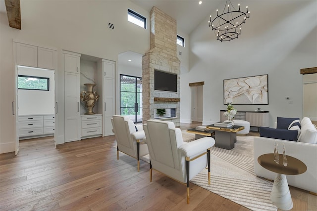 living room with a stone fireplace, high vaulted ceiling, and light hardwood / wood-style floors