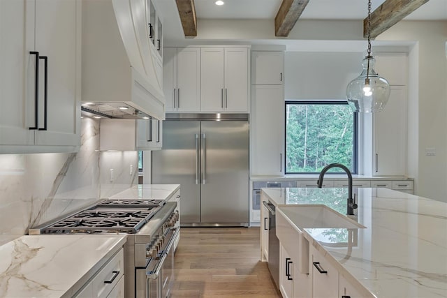 kitchen with high quality appliances, sink, hanging light fixtures, beam ceiling, and white cabinetry