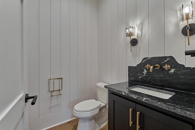 bathroom with wood walls, vanity, hardwood / wood-style flooring, and toilet