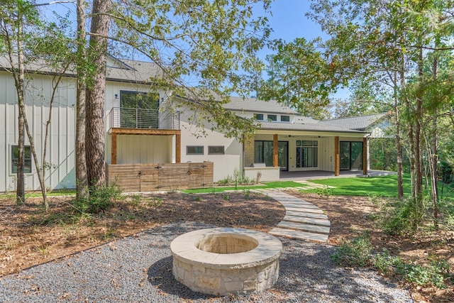 back of property with a fire pit, ceiling fan, and a patio area