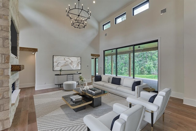 living room featuring hardwood / wood-style flooring, a towering ceiling, a fireplace, and a chandelier