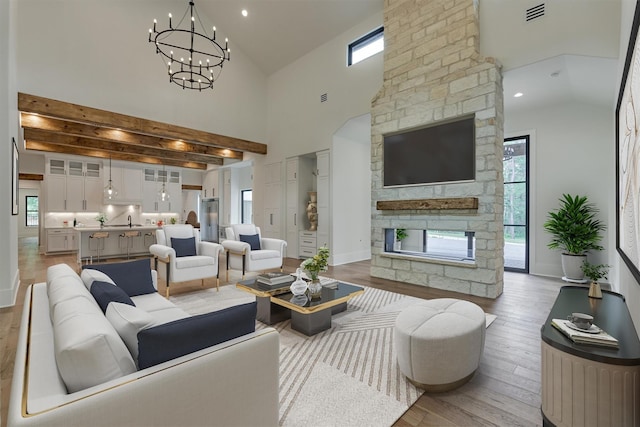 living room featuring an inviting chandelier, light hardwood / wood-style floors, high vaulted ceiling, and sink