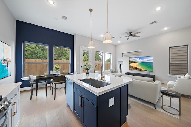 kitchen featuring sink, appliances with stainless steel finishes, a center island with sink, blue cabinets, and decorative light fixtures