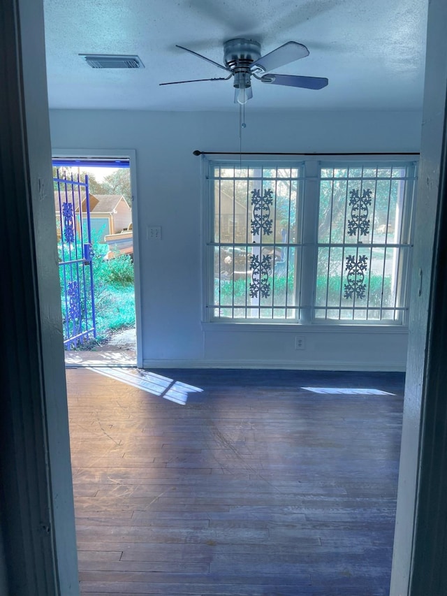 empty room with ceiling fan, a healthy amount of sunlight, and wood-type flooring