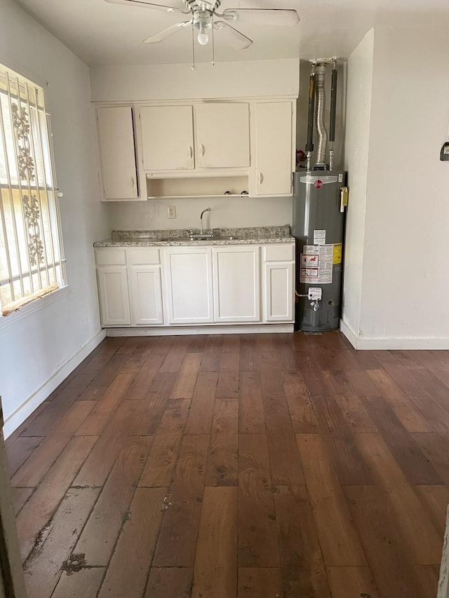 kitchen with white cabinets, gas water heater, light stone counters, and dark wood-type flooring