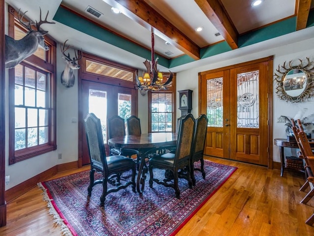 dining space featuring hardwood / wood-style flooring, french doors, beamed ceiling, and an inviting chandelier