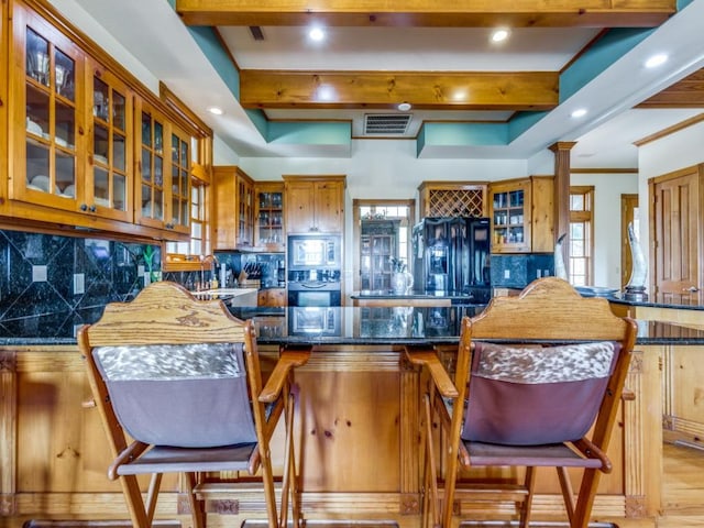 kitchen with a breakfast bar, dark stone counters, decorative backsplash, light wood-type flooring, and kitchen peninsula