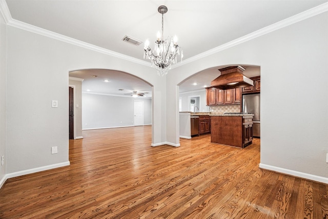 interior space with ceiling fan with notable chandelier, ornamental molding, and light hardwood / wood-style flooring