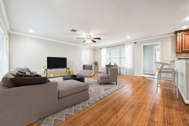 living room with light wood-type flooring, ceiling fan, and ornamental molding