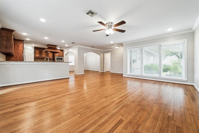 unfurnished living room with light hardwood / wood-style floors, ceiling fan, and ornamental molding