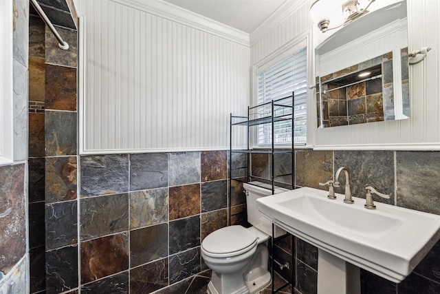 bathroom with toilet, ornamental molding, and tile walls