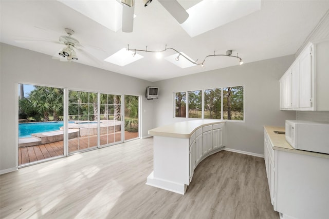 kitchen featuring white cabinets, a healthy amount of sunlight, and a skylight