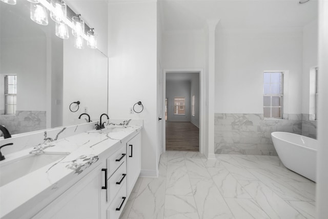 bathroom with vanity, ornamental molding, tile walls, and a tub