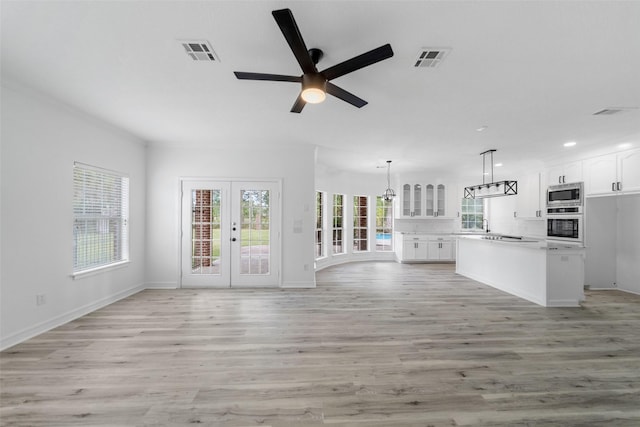 unfurnished living room with ceiling fan, light hardwood / wood-style flooring, and french doors