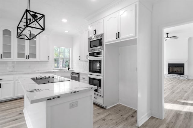 kitchen with white cabinets, appliances with stainless steel finishes, a center island, and light stone countertops