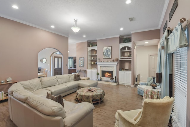 living room featuring ornamental molding, a textured ceiling, and light wood-type flooring