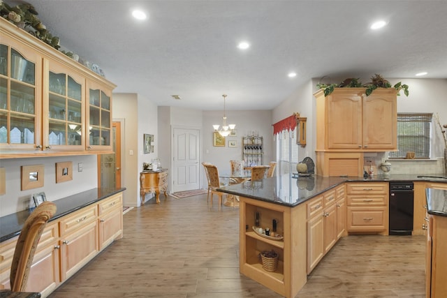 kitchen with light brown cabinets, light wood-type flooring, hanging light fixtures, and dark stone countertops