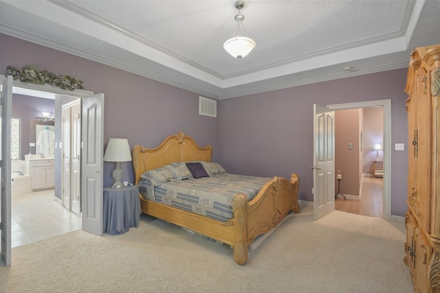 carpeted bedroom with ensuite bathroom, ornamental molding, and a tray ceiling