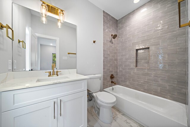 full bathroom featuring tiled shower / bath, vanity, and toilet