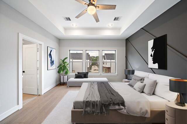 bedroom with light hardwood / wood-style floors, a raised ceiling, and ceiling fan