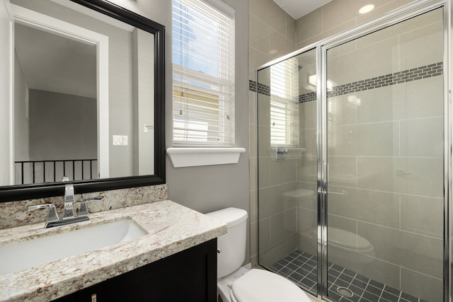 bathroom featuring toilet, plenty of natural light, vanity, and walk in shower