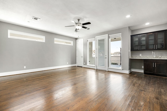 unfurnished living room featuring ceiling fan, dark hardwood / wood-style flooring, and sink