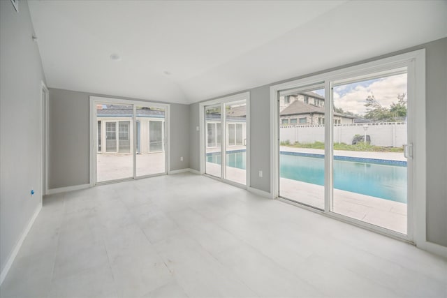 spare room with light tile patterned floors and vaulted ceiling