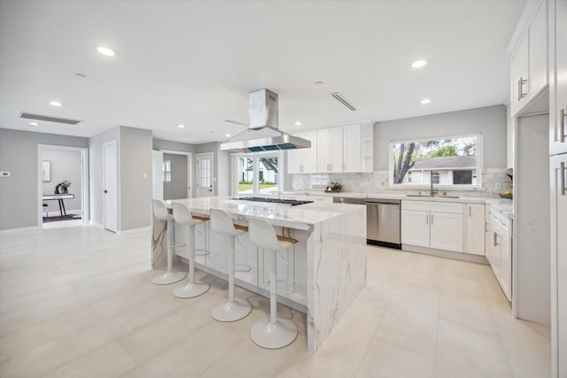 kitchen with light stone countertops, a center island, island exhaust hood, white cabinets, and appliances with stainless steel finishes