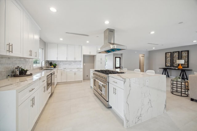 kitchen featuring white cabinetry, a large island, range with two ovens, and range hood