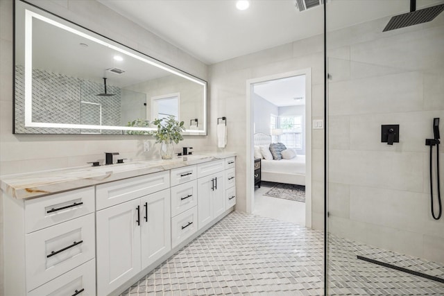 bathroom with tile patterned flooring, a tile shower, and vanity