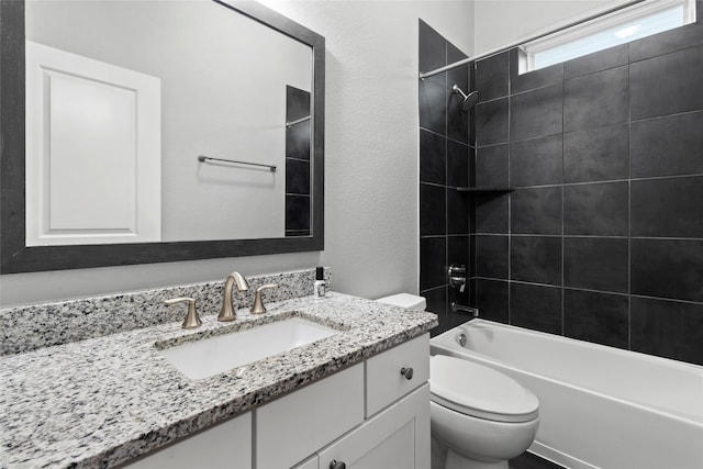 full bathroom featuring vanity, tiled shower / bath combo, and toilet