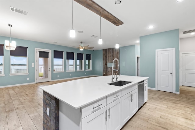 kitchen with stainless steel dishwasher, pendant lighting, sink, and a kitchen island with sink