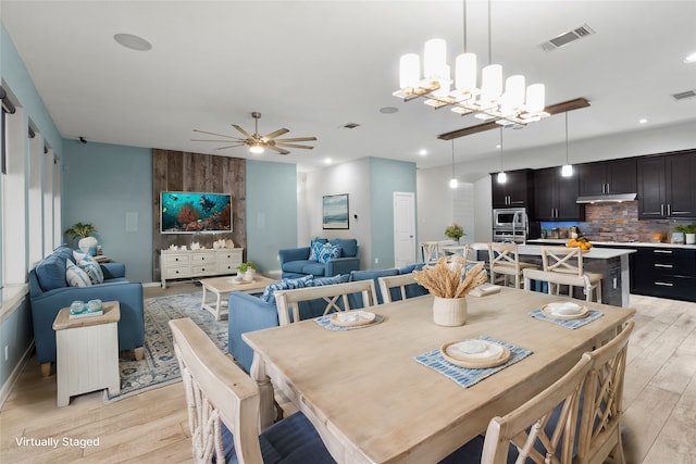 dining area with ceiling fan with notable chandelier and light hardwood / wood-style floors