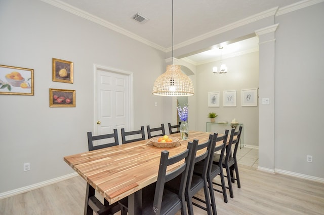 dining space with decorative columns, light hardwood / wood-style floors, a notable chandelier, and ornamental molding