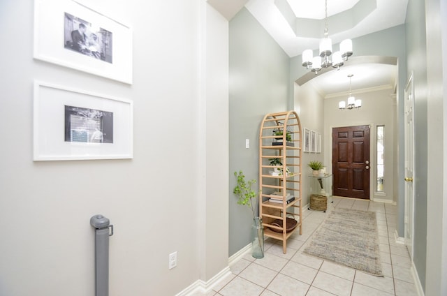 tiled foyer entrance featuring a notable chandelier and crown molding