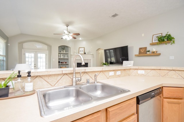 kitchen featuring french doors, ceiling fan, sink, dishwasher, and a tiled fireplace