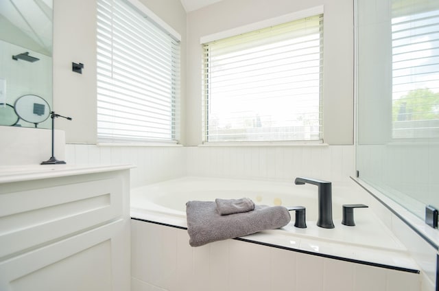 bathroom featuring vanity and tiled bath