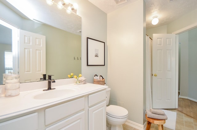 bathroom with walk in shower, vanity, a textured ceiling, tile patterned flooring, and toilet