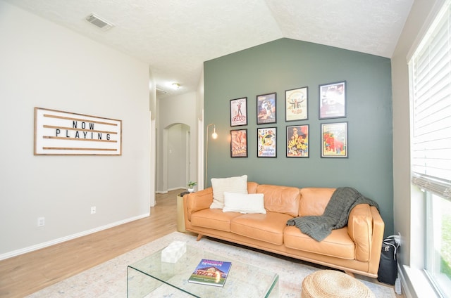 living room with a textured ceiling, vaulted ceiling, and hardwood / wood-style flooring