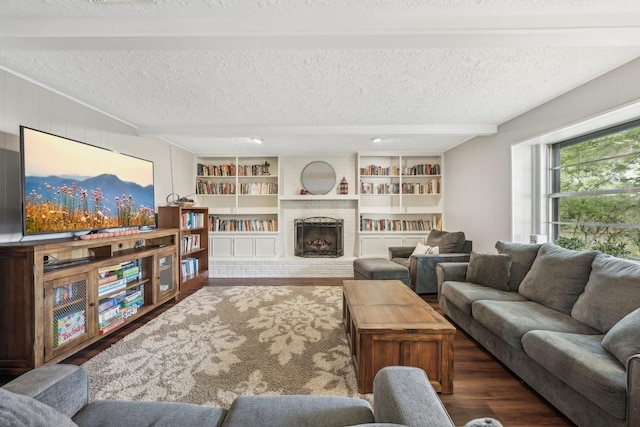 living room featuring a fireplace, built in shelves, a textured ceiling, and dark hardwood / wood-style floors