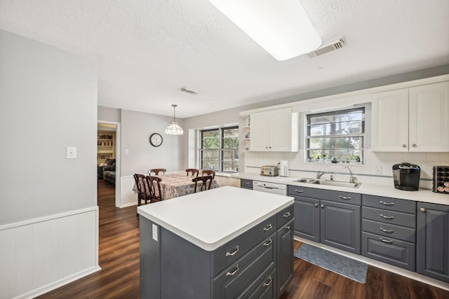 kitchen featuring white cabinetry, sink, dark hardwood / wood-style flooring, pendant lighting, and a kitchen island