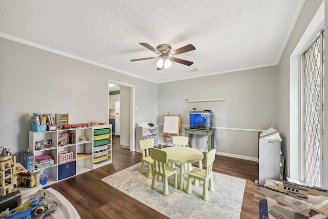 rec room with a textured ceiling, crown molding, and dark wood-type flooring