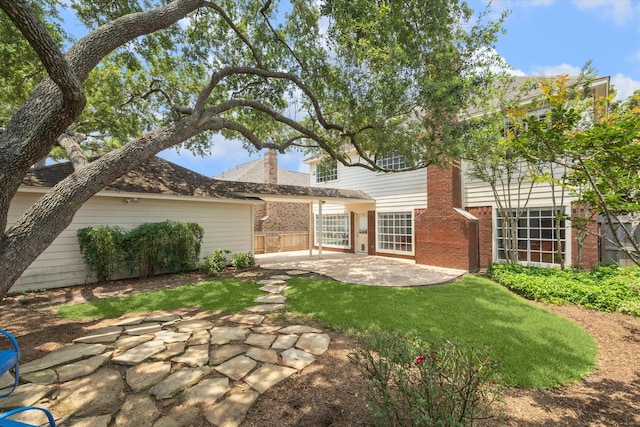 rear view of house featuring brick siding, a patio, and a chimney